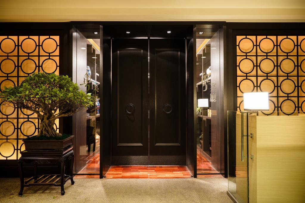 Ambassador Hotel Καοσιούνγκ Εξωτερικό φωτογραφία The photo shows an elegant entrance area featuring a set of large black double doors, which appear to be a main entryway. The walls surrounding the doors have a decorative design with circular patterns. On one side, there is a small tree in a planter