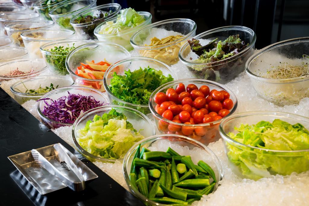 Ambassador Hotel Καοσιούνγκ Εξωτερικό φωτογραφία The photo displays a vibrant array of fresh vegetables and greens arranged in clear bowls on a bed of ice. The selection includes various leafy greens, chopped vegetables, and colorful ingredients. There are items like cherry tomatoes, purple cabbage