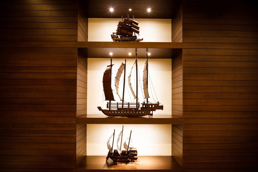 Ambassador Hotel Καοσιούνγκ Εξωτερικό φωτογραφία The photo displays three model ships arranged on shelves with a warm wood background. Each ship has distinct features and varying sizes, showcasing different designs. The top ship has a traditional Asian style with sails, the middle ship appears to b