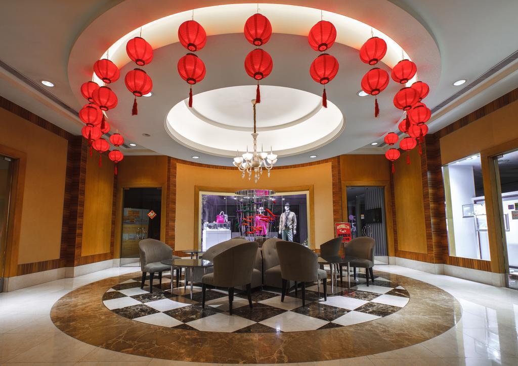 Ambassador Hotel Καοσιούνγκ Εξωτερικό φωτογραφία The photo depicts an elegant interior space featuring a circular seating area. The ceiling is adorned with several red lanterns, creating a festive atmosphere. There is a circular chandelier in the center, contributing to the overall ambiance. The fl