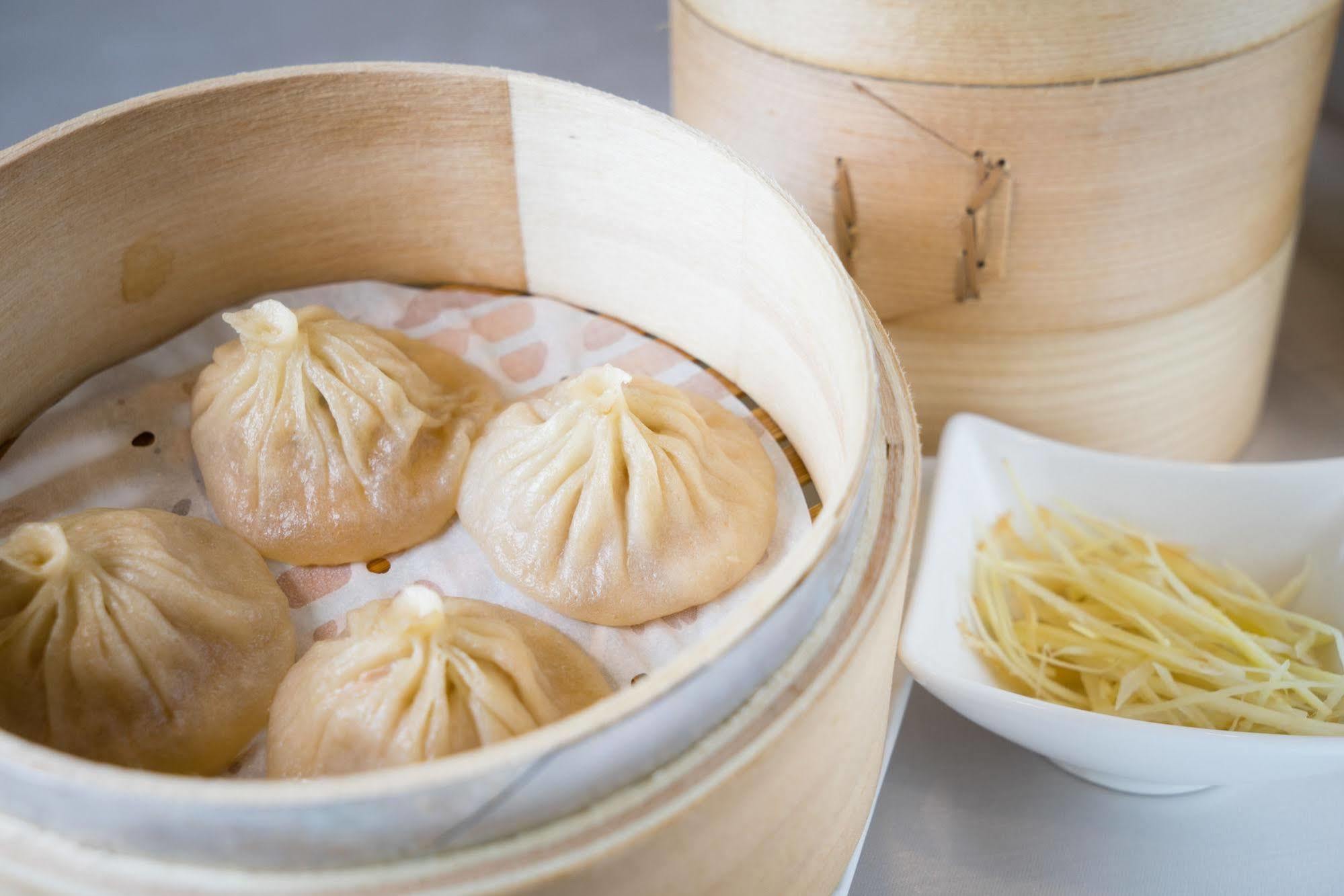 Ambassador Hotel Καοσιούνγκ Εξωτερικό φωτογραφία The photo shows a bamboo steamer containing several dumplings, known as xiaolongbao, which are soup dumplings traditionally filled with meat and broth. The dumplings are arranged neatly on a layer of parchment paper inside the steamer. Next to the st