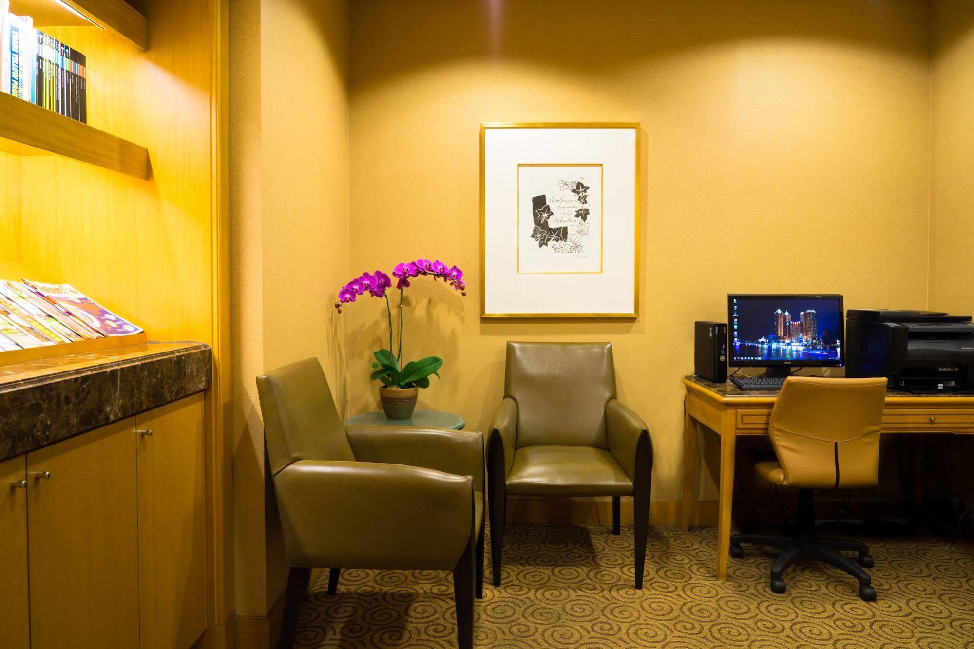 Ambassador Hotel Καοσιούνγκ Εξωτερικό φωτογραφία The photo shows a cozy corner of a room, which appears to be a waiting or lounge area. There are two stylish chairs positioned near a small table. A potted plant with purple flowers adds a touch of color and freshness to the space. On the wall, there