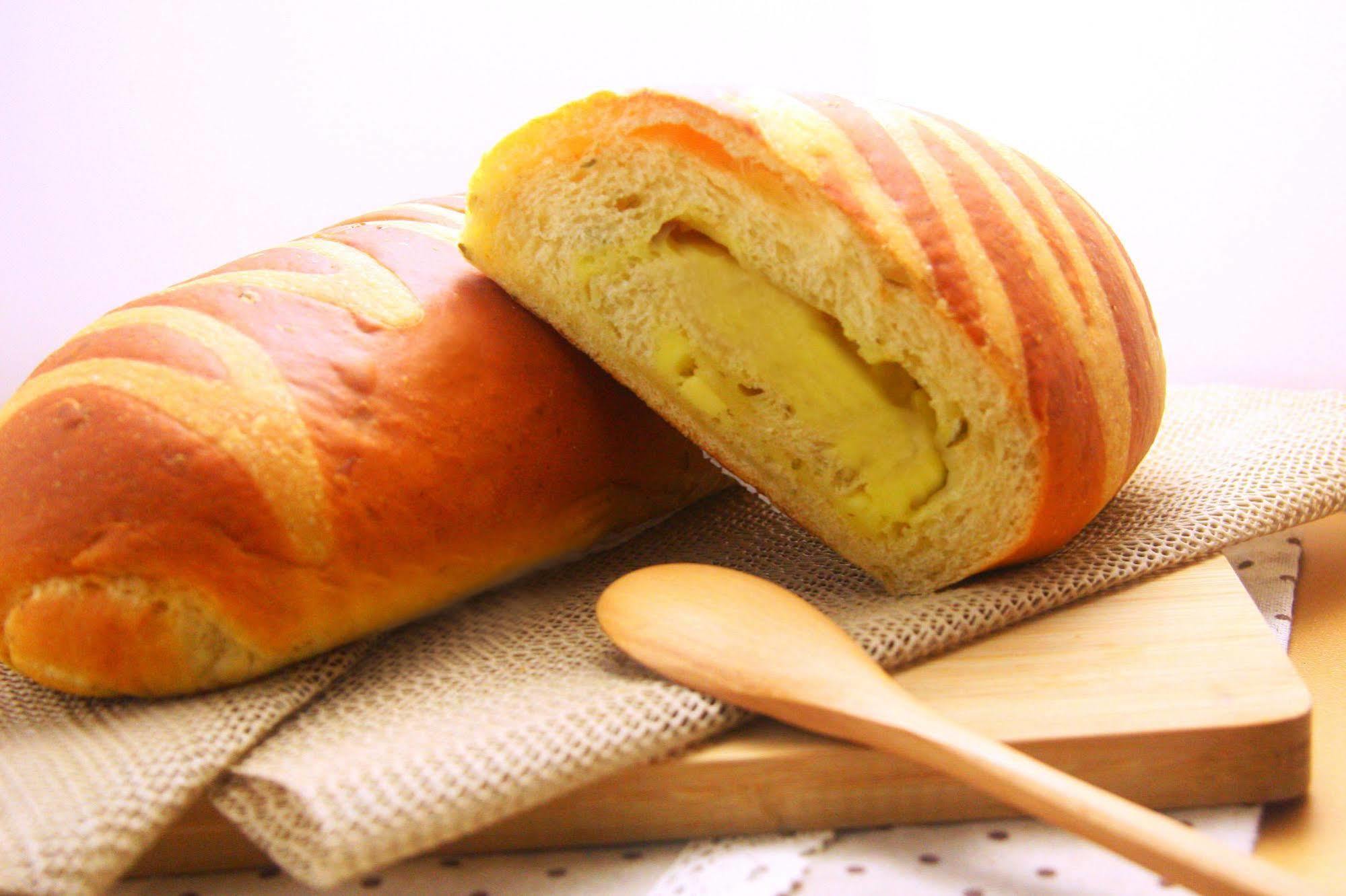 Ambassador Hotel Καοσιούνγκ Εξωτερικό φωτογραφία The photo shows a loaf of bread that has a golden-brown crust with striped patterns on its surface. One loaf is partially sliced open, revealing a soft, yellow filling inside, which suggests that it might be flavored or sweetened. The bread is placed