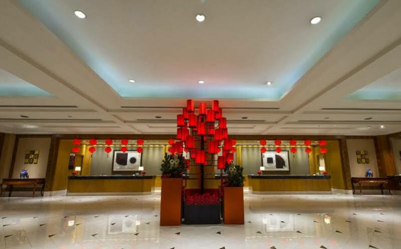 Ambassador Hotel Καοσιούνγκ Εξωτερικό φωτογραφία The photo shows a hotel lobby with a modern and elegant design. In the center, there is a striking red display, likely made up of lanterns or decorative elements, creating a vibrant focal point. The lobby features a polished floor that reflects the l